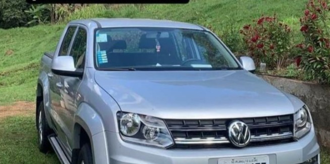 camionete amarok cinza estacionada em um gramado 