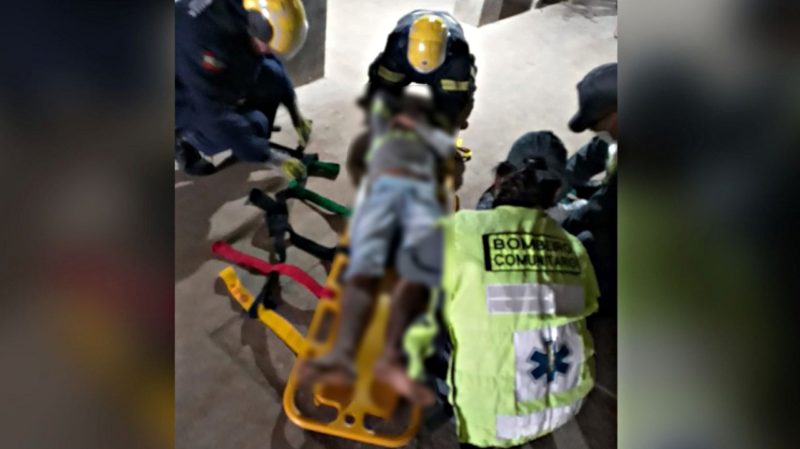 trabalhador deitado na maca com os bombeiros em volta