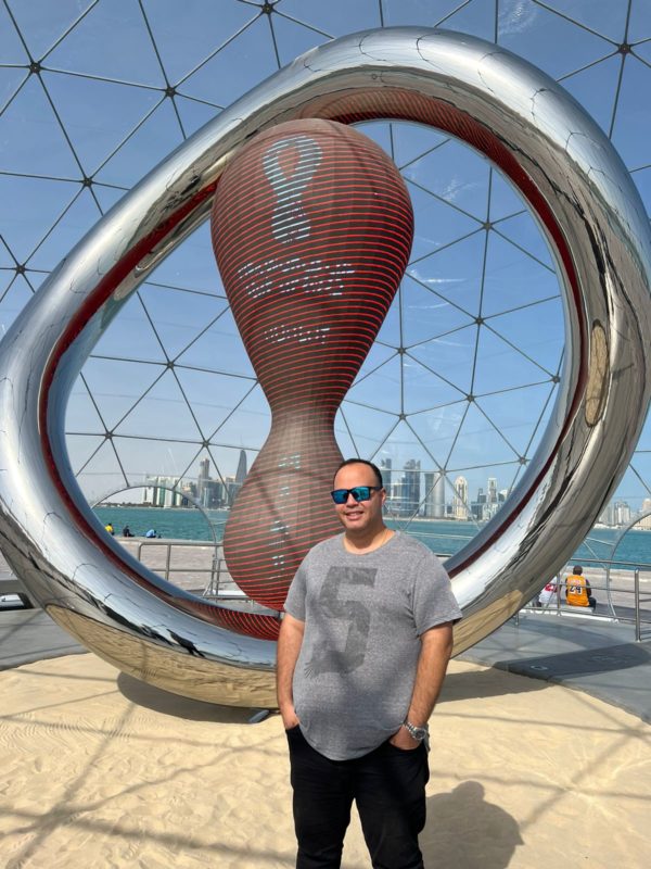 Gabriel posa em frente a rel&oacute;gio com contagem regressiva para a Copa do Mundo, localizado na orla de Doha – Foto: Arquivo pessoal/ND