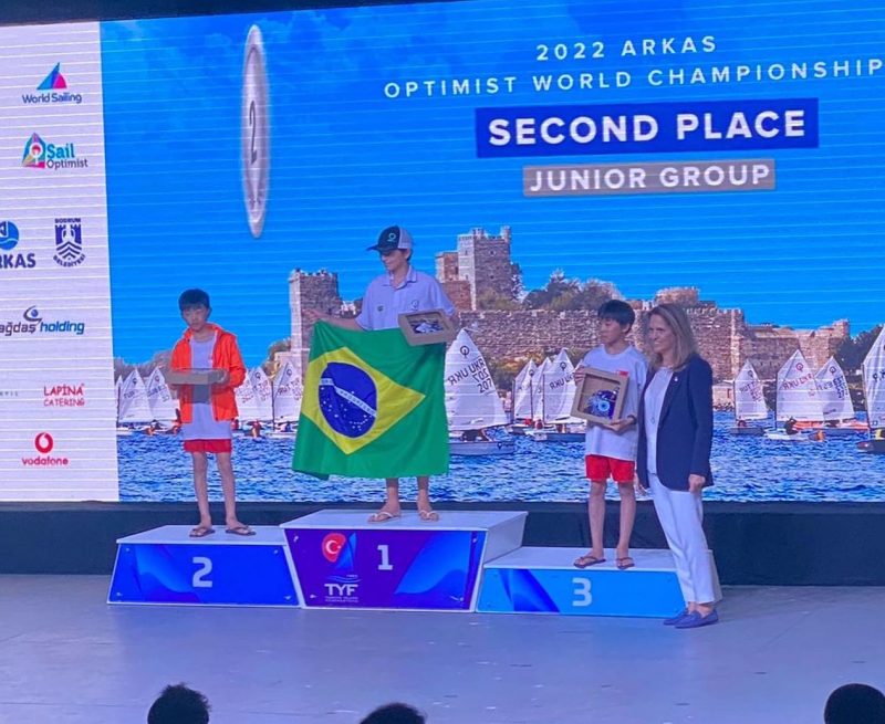 O manezinho Davi neves comemora com a bandeira do Brasil t&iacute;tulo de Campe&atilde;o Mundial Junior de Vela – Foto: divulga&ccedil;&atilde;o/optibra