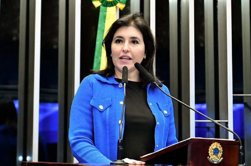 Plano de 25 anos será coordenado pelo Ministério do Planejamento e Orçamento, liderado pela ministra Simone Tebet, foto mostra ministra falando em microfone com casamento azul e blusa preta