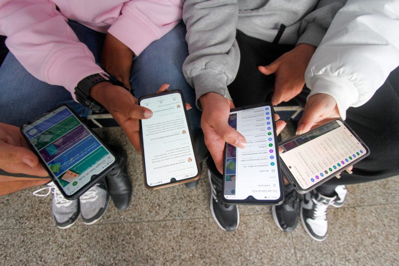 Alunos segurando aparelho celular