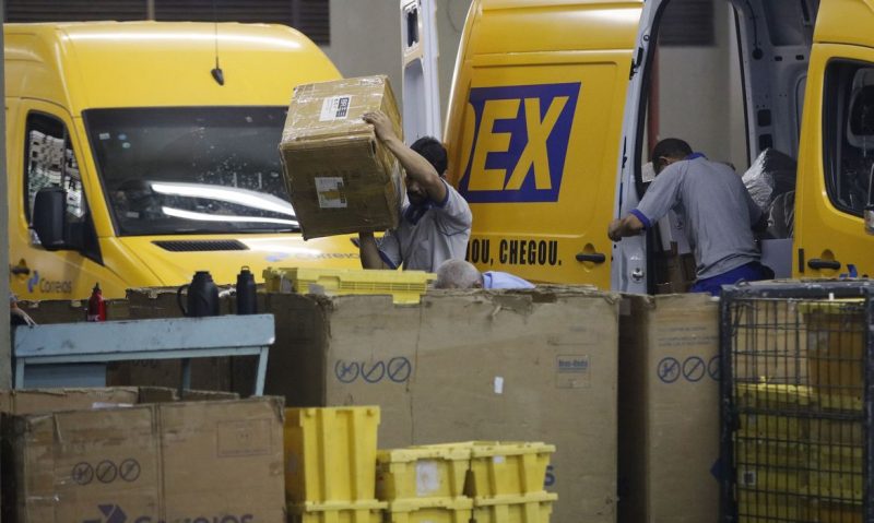 Correios de 3 estados entrariam em greve. Na foto, funcionários descarregam mercadorias de uma van plotada com o simbolo do sedex. 