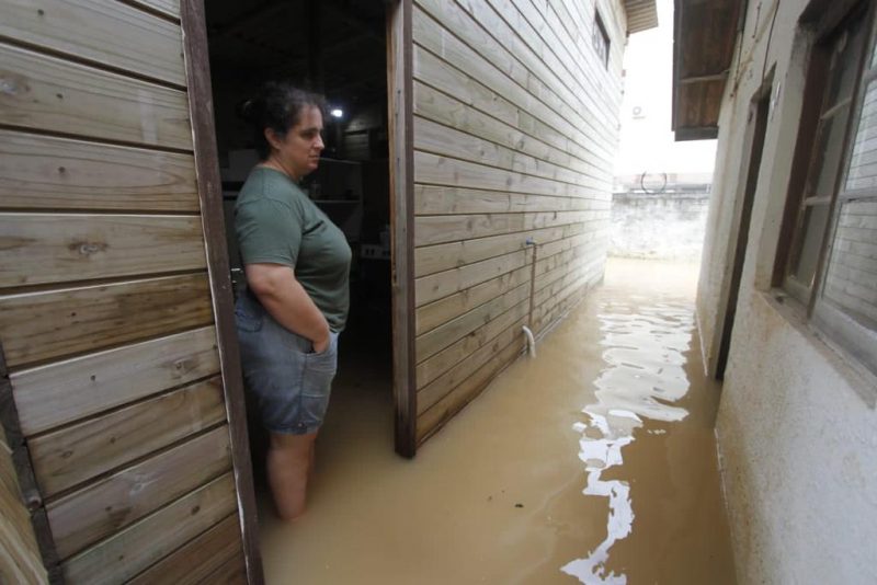 Moradora olha para rua de sua casa enquanto &aacute;gua toma conta no Jardim Eldorado, em Palho&ccedil;a – Foto: Leo Munhoz/ND
