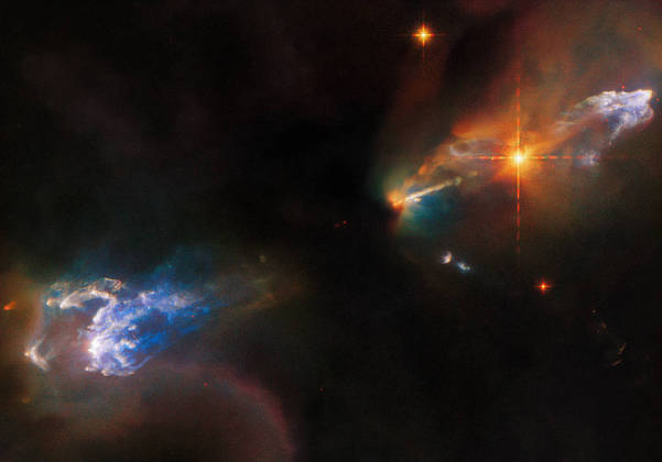 An image taken by the Hubble Space Telescope shows the complexity of newborn stars.  The star system is not visible in the center of the image due to the thick clouds that hide it, but Herbig-Haro objects HH 1, a glowing cloud above the star, and HH 2, a cloud in the lower right corner can be observed - Photo: Reproduction / ESA / Hubble / NASA