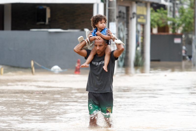 Er&ocirc;ncio Silva Ribeiro carrega um dos tr&ecirc;s filhos: a fam&iacute;lia perdeu todos os pertences na enchente – Foto: Leo Munhoz/ND