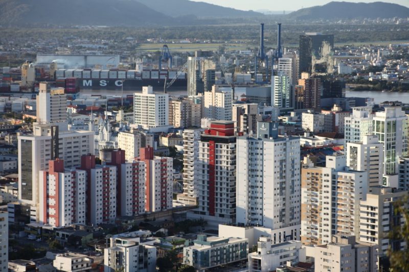 Visão panorâmica da cidade de Itajaí, destaque do Censo 2022, com foco nos prédios e o porto do município ao fundo