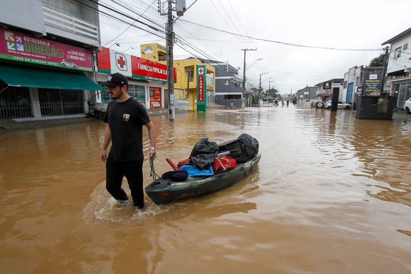 Em Florian&oacute;polis, morador tira as coisas de casa com aux&iacute;lio de um bote em meio a &aacute;gua – Foto: Leo Munhoz/ND
