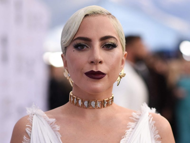 Cantora Lady Gaga aparece olhando para frente e séria com colar e look branco admitiu que é viciada em chá verde