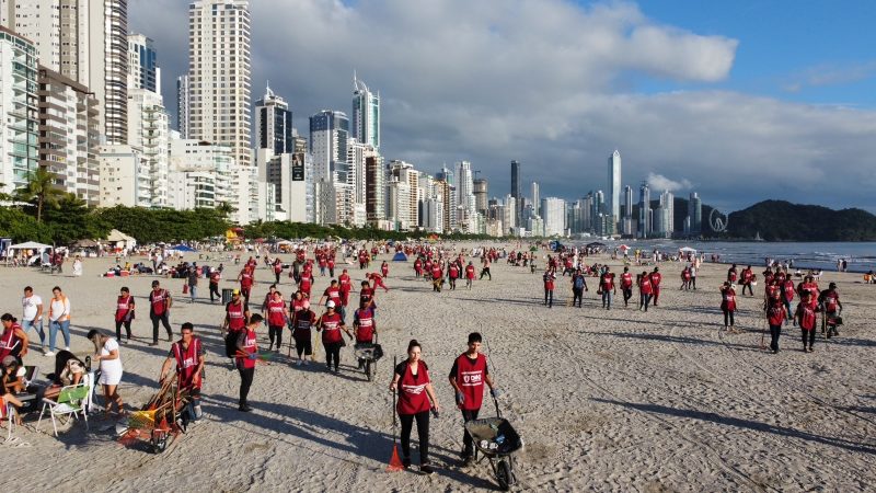 Imagem mostra equipe da limpeza em força tarefa para limpara praia Central de Balneário Camboriú