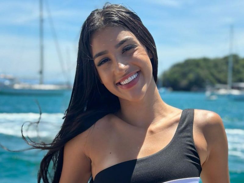 Bia Miranda em foto com blusa preta e com mar por trás