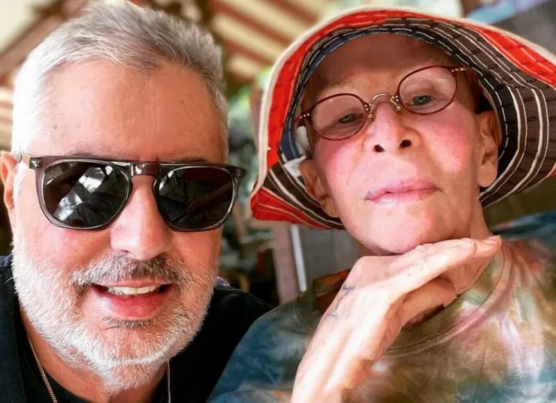na foto, Roberto de Carvalho aparece de óculos e Rita Lee aparece de chapéu e óculos à direita