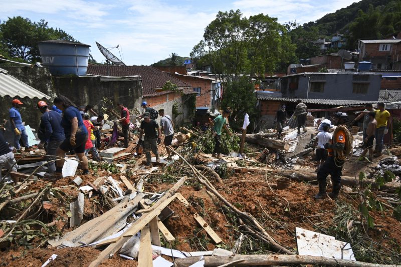 Pessoas removem detritos em uma &aacute;rea afetada por enchentes em Barra do Sahy, distrito de S&atilde;o Sebasti&atilde;o – Foto: NELSON ALMEIDA / AFP