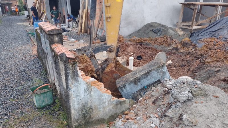 muro cai e homem fica sob os escombros