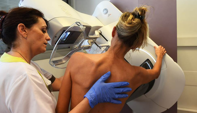 Imagem mostra mulher ao lado de médico realizando mamografia 