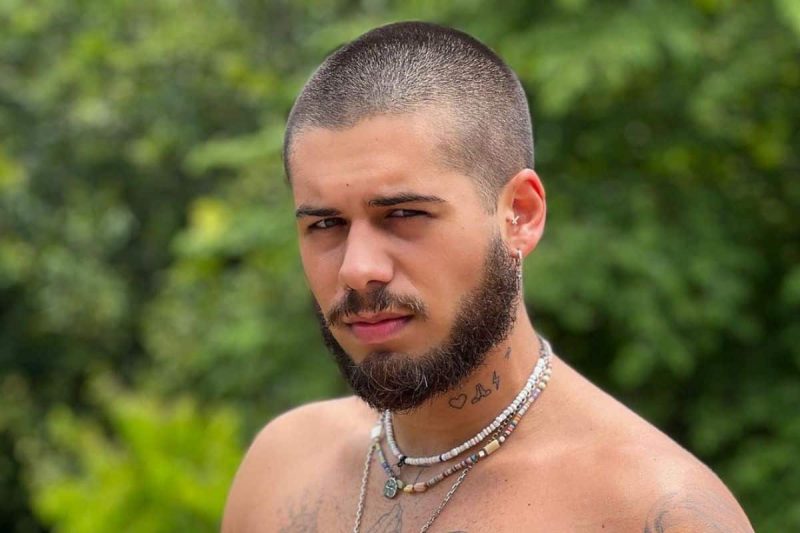 Cantor Zé Felipe aparece na foto com o cabelo raspado e barba com ar sério e olhando para frente 