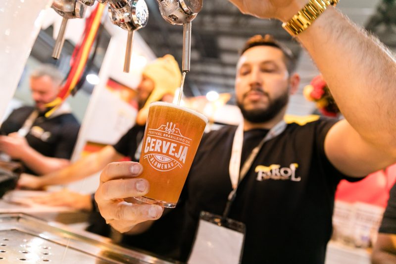 Homem enchendo copo durante Festival Brasileiro da Cerveja em Blumenau