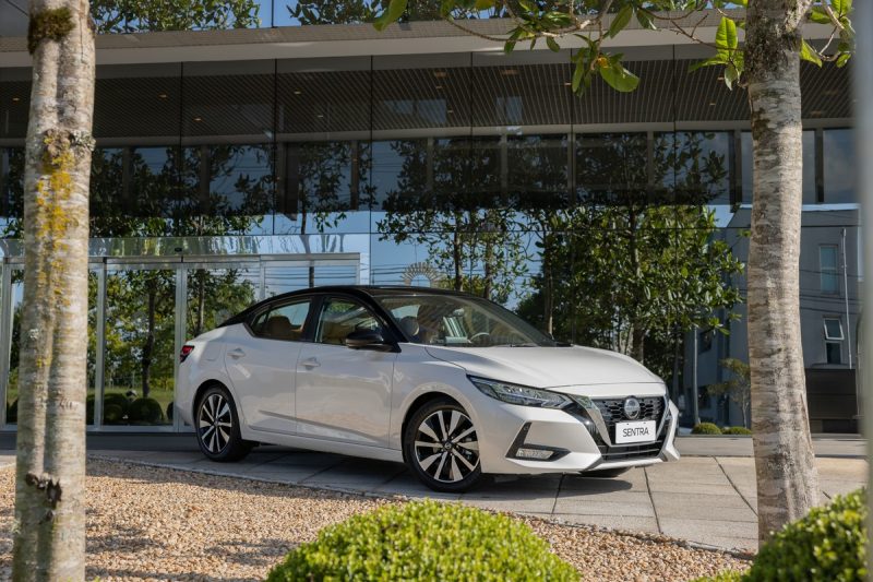 Na imagem, carro da Nissan elétrico aparece estacionado na frente de hotel
