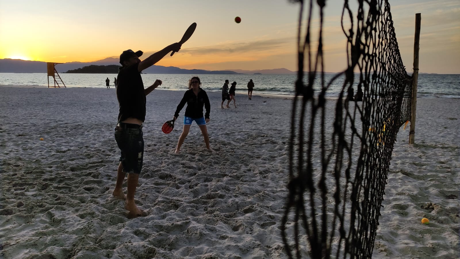 Pessoas jogando basquete em quadra poliesportiva pública na orla