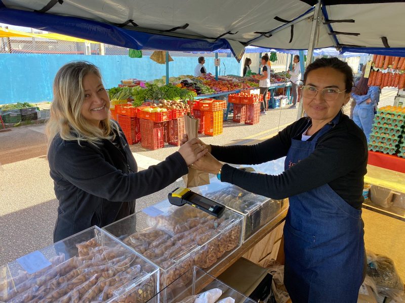 A dentista Ana Cristina Cabral, 49 anos, comprando produtos naturais na banca da feirante Miraci Gomes, 44 anos, a ca&ccedil;ula da feira do Estreito, em Florian&oacute;polis – Foto: Windson Prado/ND