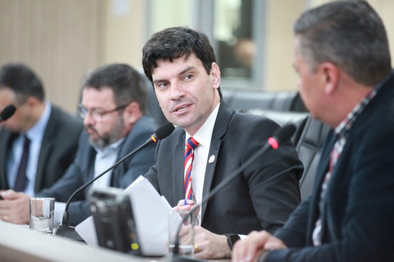 Foto do delegado-geral da Polícia Civil de Santa Catarina, Ulisses Gabriel sentado em uma mesa olhando para o lado