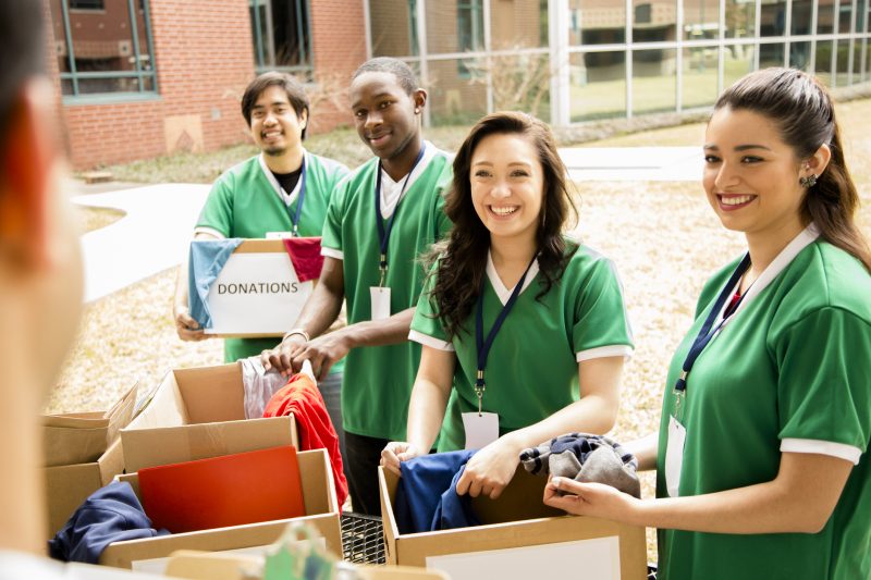 Voluntários recolhendo doações de roupa na escola