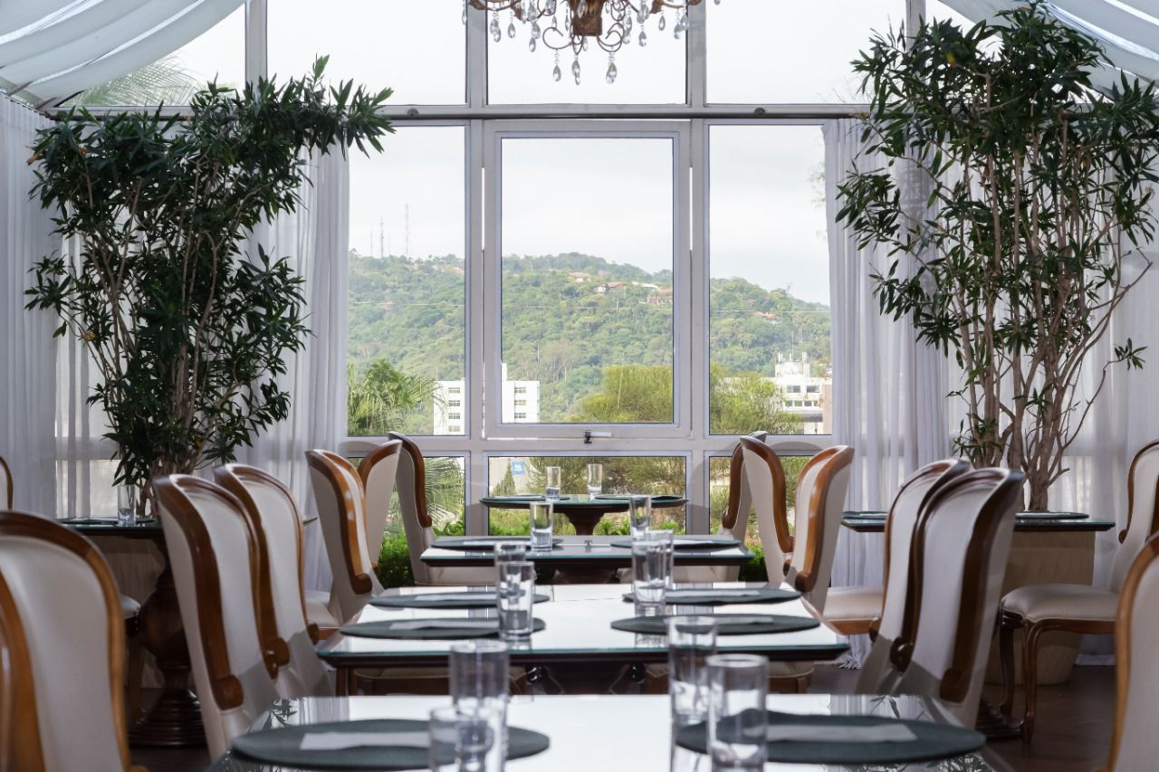 Um restaurante com teto preto e uma grande mesa com um monte de plantas  verdes.