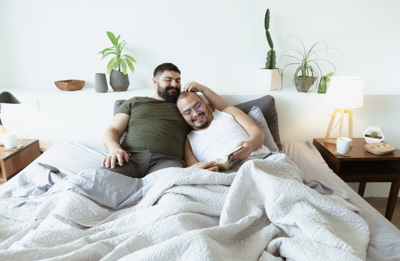 Amizade e relacionamento: Casal feliz deitado na cama lendo um livro