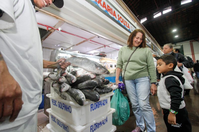 A dom&eacute;stica Edith Barreto, 55, e o seu neto Miguel, 4, estavam curiosos para saber o tamanho das tainhas – Foto: Leo Munhoz/ND