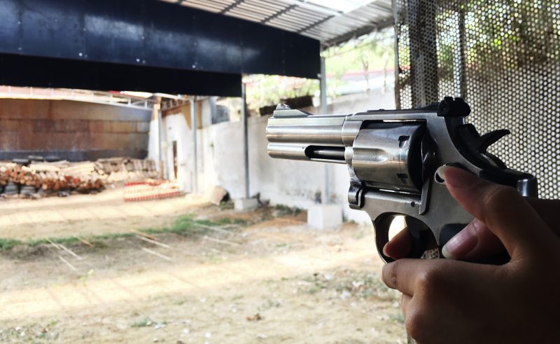 Pessoa segurando arma de fogo na direção de um alvo