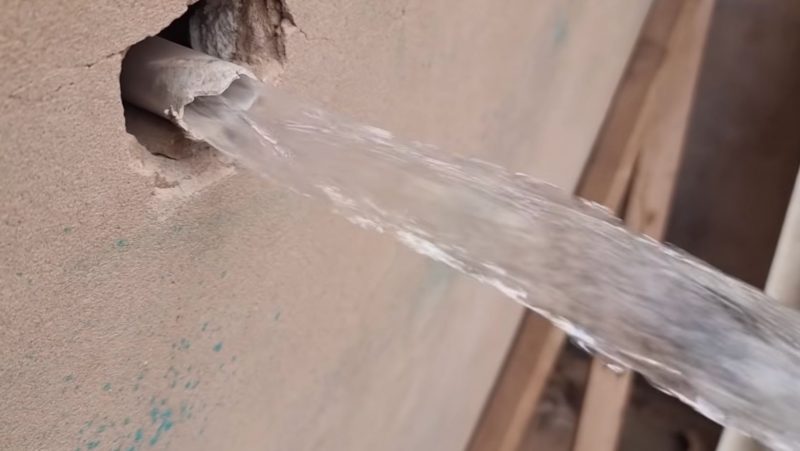 Pedreiro mostra cano na parede jorrando água