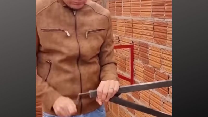 Pedreiro engata parte do andaime em tijolo do próprio muro