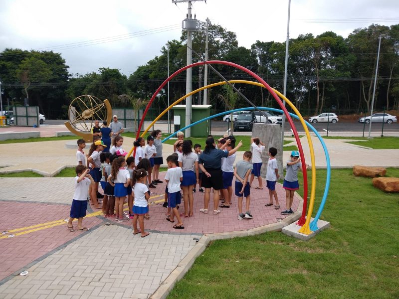 Foto mostra dezenas de crianças embaixo de uma estrutura de ferro no Parque Astronômico de Criciúma. O local é uma ótima opção de passeio com crianças no Sul de Santa Catarina. 