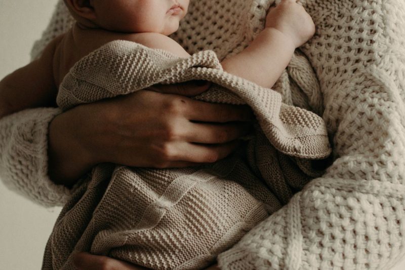 Domicílios são gerenciados por mães solo, foto mostra mulher segurando bebê no colo