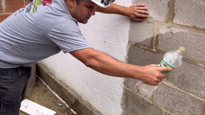 Pedreiro joga água no muro, após impermeabilizar