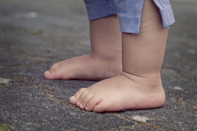 Foto mostra pés de criança pequena descalça no chão