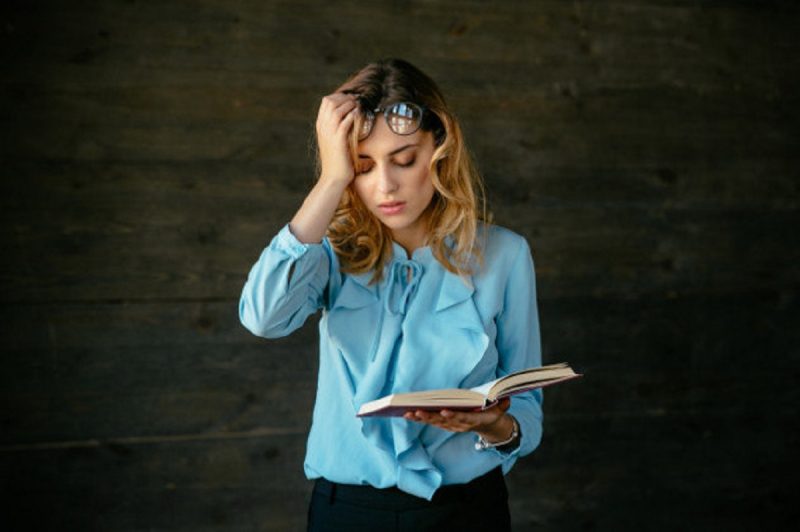 Mulher tentando ler um livro com a visão embaçada 