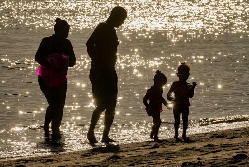 Imagem de uma família com dois filhos na praia