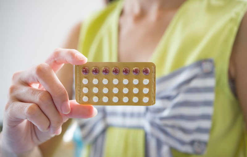 Mulher segurando cartela de anticonceptivos 