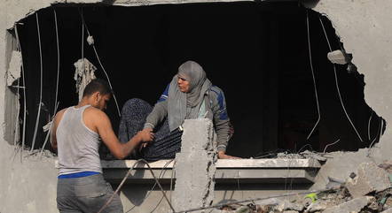 A man helps a woman out of a building after attacks in Rafah in the southern Gaza Strip - Photo: KHATIB SAYS/AFP