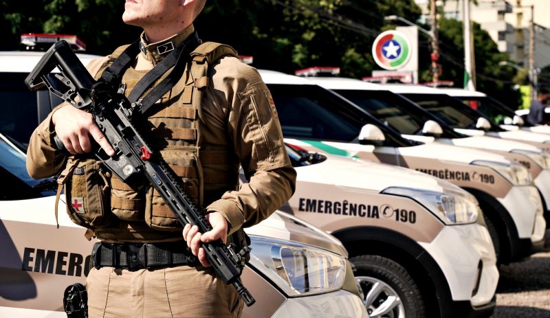 Policial militar armado na frente de várias viaturas da Polícia Militar de Santa Catarina em busca de bandido