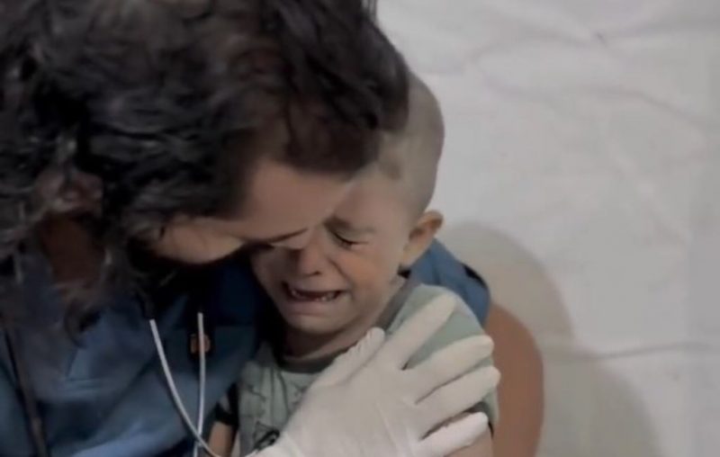 Criança palestina em estado de choque é consolada por médico após bombardeio em Gaza