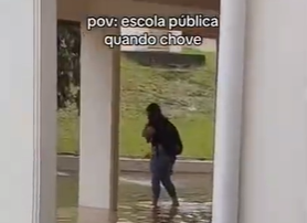 Estudante andando em meio alagamento de uma escola em Lages