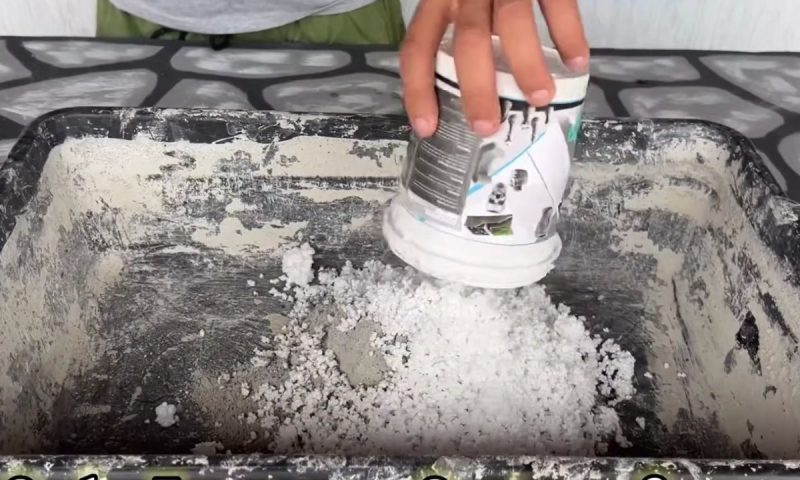 Pedreiro despeja isopor em uma bandeja onde vai entrar cimento em seguida