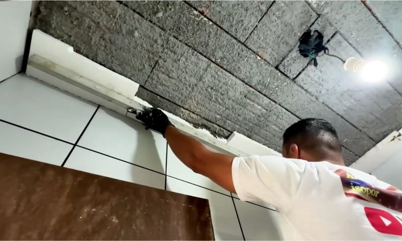 Isopor em placas sendo instalado como forro por pedreiro em banheiro
