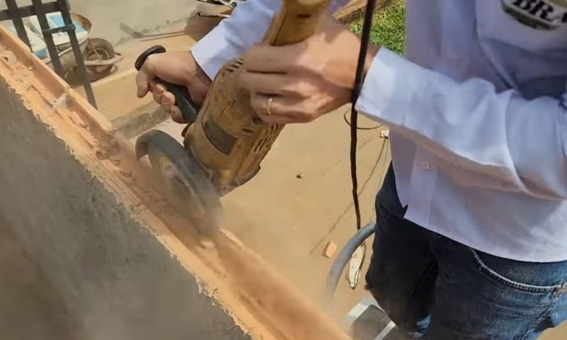 Pedreiro serrando pare de cima de uma fileira de tijolos de um muro