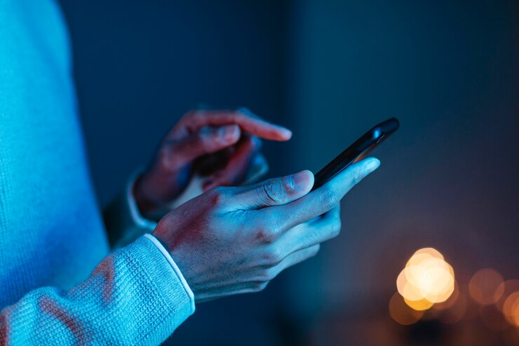 Pessoa segurando o celular em uma das mãos e com a outra tocando na tela. Ela veste uma roupa de tecido moletom