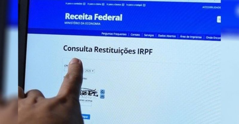 homem apontando para site de consulta de restituições de imposto de renda