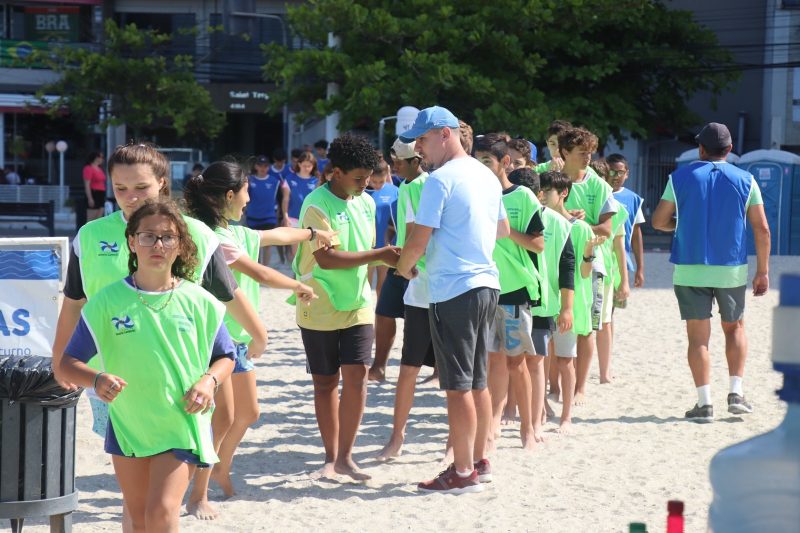 Crianças com colete correndo na praia de Balneário Camboriú durante evento 