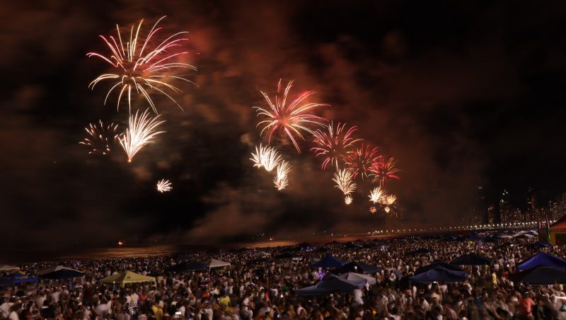 Praia Central de Balneário Camboriú lotada, enquanto banhistas assistem show de fogos de artifício do Réveillon